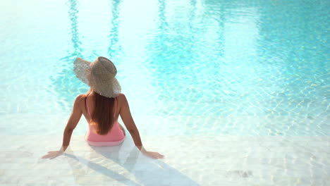 Rear-View-of-Woman-on-Holiday-Sitting-in-Shallow-End-of-Swimming-Pool