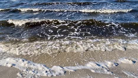 Die-Wellen-Entlang-Der-Küste-Rollen-Langsam-In-Zeitlupe-über-Den-Sand