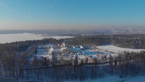 Aerial-view-of-the-Pazaislis-monastery-and-the-Church-of-the-Visitation-in-Kaunas,-Lithuania-in-winter,-snowy-landscape,-Italian-Baroque-architecture,-flying-around-the-monastery,-far-away-from-it