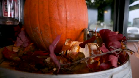 Orange-Pumpkin-On-A-Pile-Of-Colorful-Dried-Maple-Leaves---Halloween-Display---orbiting-shot