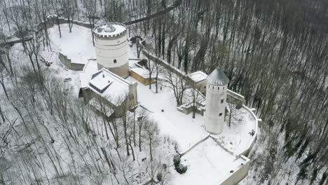 Drone-aerial-of-the-fairy-tale-castle-Plesse-in-winter-with-a-huge-amount-of-snow-on-a-beautiful-mountain-near-Bovenden,-Germany,-Europe