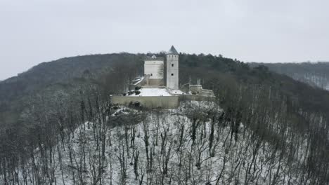 The-fairy-tale-castle-Plesse-in-winter-with-a-huge-amount-of-snow-on-a-beautiful-mountain-near-Bovenden,-Germany,-Europe