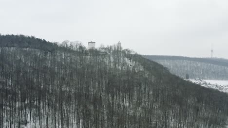 Antena-De-Drones-Del-Castillo-De-Cuento-De-Hadas-Plesse-En-Invierno-Con-Una-Gran-Cantidad-De-Nieve-En-Una-Hermosa-Montaña-Cerca-De-Bovenden,-Alemania,-Europa