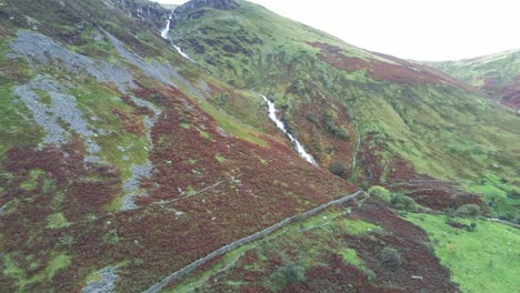 Idyllic-Snowdonia-mountain-range-Aber-falls-waterfalls-national-park-aerial-low-moving-through-countryside-view