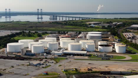 Aerial-of-oil-and-gas-fuel-refinery-storage-tanks-at-Wilmington-USA-port,-Delaware-Memorial-Bridge-in-distance