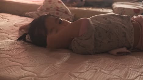 Cute-Asian-baby-waking-up-and-drowsy-on-mattress-at-home