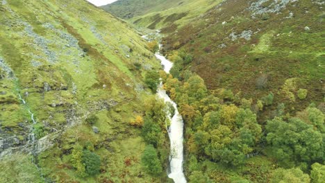 Idyllic-Snowdonia-mountain-range-Aber-falls-waterfalls-national-park-aerial-view-fast-pull-back-reveal