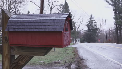 Pan-from-right-to-left-over-barn-road-revealing-close-up-of-red-mail-box-shaped-like-a-miniature-barn