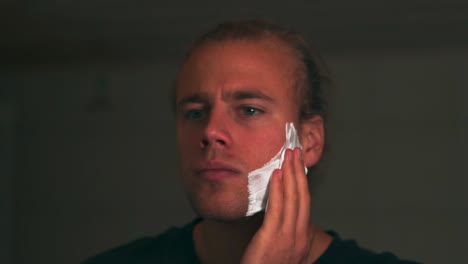 Slow-motion-shot-of-young-man-putting-shaving-foam-onto-his-beard