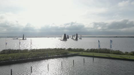 Fly-towards-a-big-group-of-sailboats-during-a-sailboat-race-at-the-Sneekermeer