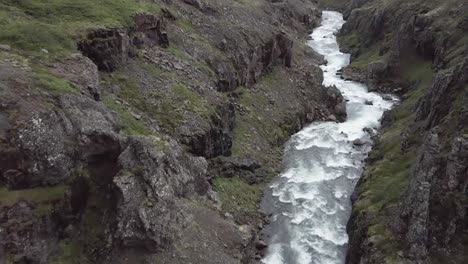 Aerial-flying-through-wild-valley-with-whitewater-rapids-and-rocky-cliffs