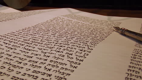 Yad-Points-to-Hebrew-in-Torah-on-Bimah,-Close-Up