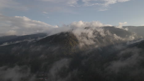 Szenische-Luftaufnahmen-Eines-Berggipfels,-Der-Mit-Dampfwolken-Und-Nebel-Bedeckt-Ist-Und-Vom-Sonnenaufgang-4k-Beleuchtet-Wird