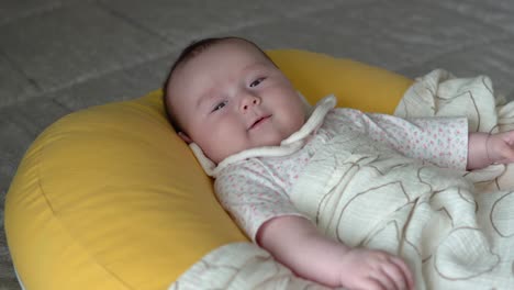 Säuglingsbaby-Lächelt,-Während-Es-Auf-Einem-Weichen-Kissen-Liegt