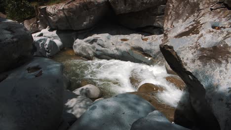 Foamy-water-flowing-in-slow-motion-through-big-rocks-on-the-river