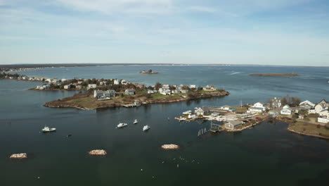 Drone-shot-of-fishing-town-on-peninsula-surrounded-by-sea-water,-Maine