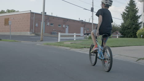 A-kid-rides-his-bike-up-the-street-in-the-suburbs-on-a-summer-day-in-slow-motion