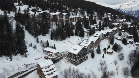 Aerial-view-partment-buildings-in-ski-resort-in-Swiss-Alps,-tilt-up-reveal