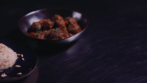 Dawood,-Daoud-Basha-Dish---Plate-Of-Vermicelli-Rice-Garnished-With-Pine-Nuts-And-A-Bowl-Of-Meatballs-In-Tomato-Gravy-Served-On-A-Table