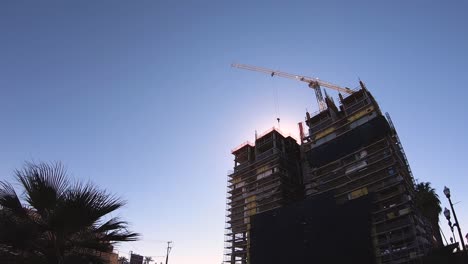 A-crane-on-top-of-high-rise-construction-moves-material-from-one-side-of-the-building-to-another,-Tempe,-Arizona