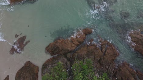 Ascending-shot-drone,-aerial-birds-eye-view-coastline-of-granite-rocks-tropical-ocean-and-beach