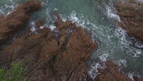 static-camera-locked-birds-eye-view-drone-shot-of-tropical-coastline-with-granite-rock-and-ocean-and-jungle