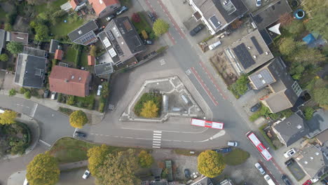 Top-down-aerial-of-buses-parking-at-bus-stop-in-green-town