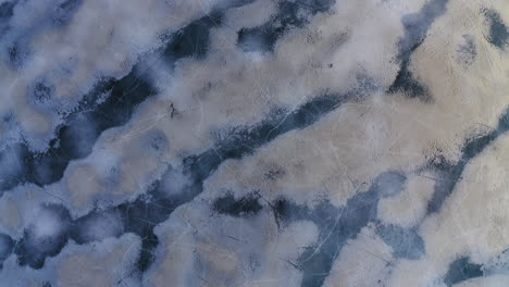 Drone-shot-of-black-ice-formations-on-an-icy-lake