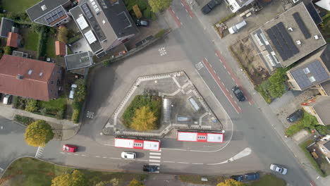 Top-down-aerial-of-traffic-driving-around-bus-station---drone-lifting-up