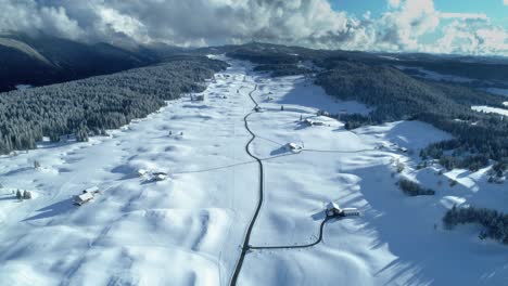 Winter-beautiful-drone-mountain-view-of-a-big-and-snowy-valley-with-road