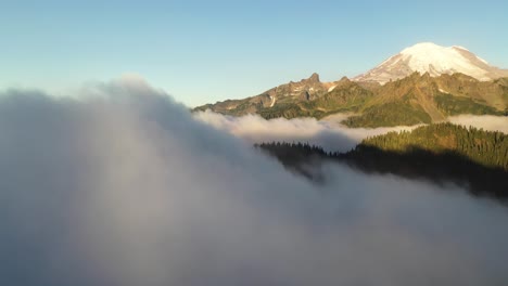 Fliegen-über-Nebel-Im-Tal-Unter-Sonnigem-Und-Schneebedecktem-Mount-Rainier-Summit,-USA-Washington-State
