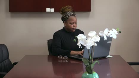 Mujer-Negra-De-40-Años-Sentada-En-La-Oficina-Escribiendo-En-La-Computadora,-Teletrabajando,-Nueva-Normalidad