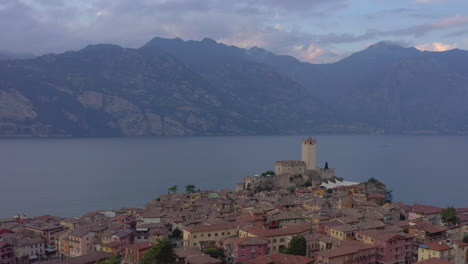 Descending-aerial-shot-overlooking-Scaligero-Castle,-Garda-Lake-and-the-surrounding-mountains