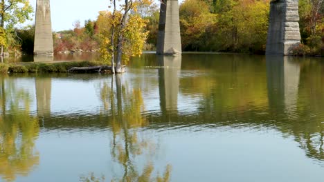 Wind-gently-ripples-across-the-water-in-front-of-the-supports-of-an-overhead-bridge