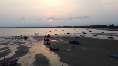 AERIAL:-Fishing-Boats-stuck-on-sand-at-low-tide-on-the-coast-of-the-ocean-at-Sunset