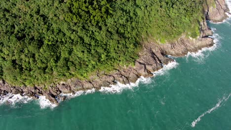 Aerial-view-of-a-jagged-rock-island,-surrounded-with-lush-green-nature-and-Hong-Kong-bay-water