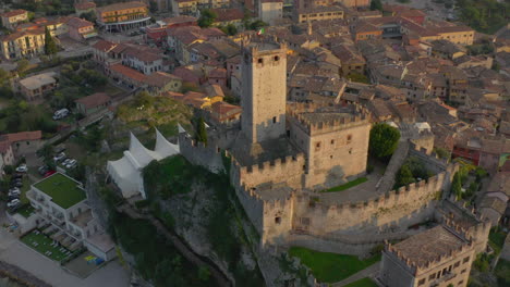 Slow-aerial,-reveal-shot-of-the-Castello-Scaligero-castle-located-near-lake-Garda,-Italy