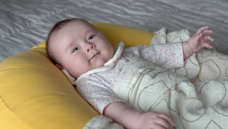 Lovable-Infant-Baby-lying-on-a-cushion-on-Bed-Smiling---close-up