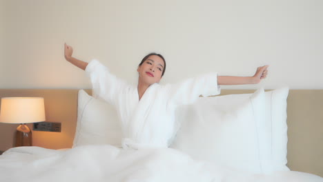 Rise-and-shine-from-a-luxurious-hotel-suite-bed,-an-attractive-woman-stretches
