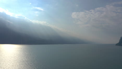 Breite-Luftaufnahme-Der-Atemberaubenden-Landschaft-Des-Gardasees-Mit-Dramatischem-Licht,-Das-über-Die-Berge-Strömt