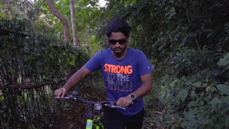 boy-man-walking-with-a-cycle-in-deep-jungle-slow-motion-front-camera