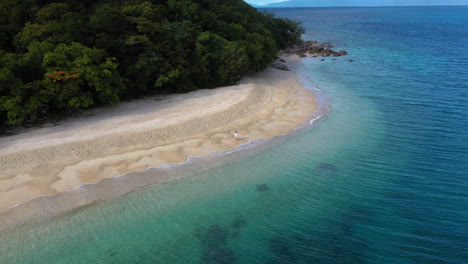 Revealing-drone-shot-of-woman-walking-on-Nudey-Beach-on-Fitzroy-Island