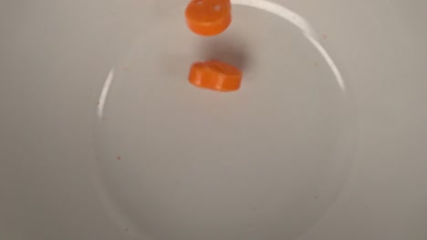 Orange-skulls-and-bones-shaped-candy-falling-on-a-white-plate