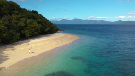 Wide-rotating-drone-shot-of-woman-walking-on-Nudey-Beach-on-Fitzroy-Island