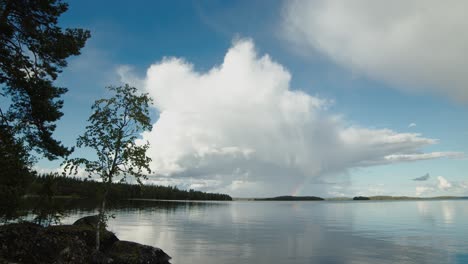Lapso-De-Tiempo-De-Cumulus-De-Nube-De-Tormenta-Sobre-El-Lago-Nasijarvi-Finlandia-Con-Abedul-En-Primer-Plano