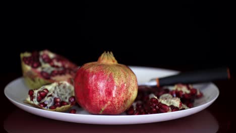Pomegranate-fruit-and-red-seeds-served-on-white-plate,-antioxidant-vitamins