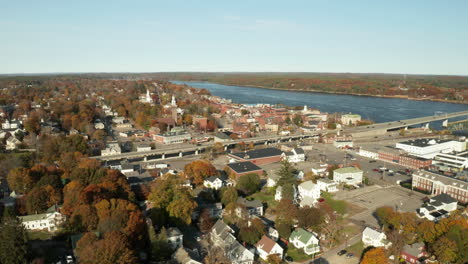 Drone-shot-of-city-on-river-banks-in-autumn,-Bath,-Maine