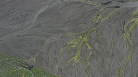 Drone-Aerial-tilt-down-from-brown-Icelandic-mountain-to-grassy-green-field