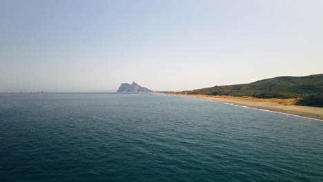 Bucle-Cinematográfico-De-Olas-De-Playa-Con-Roca-De-Gibraltar-En-El-Fondo