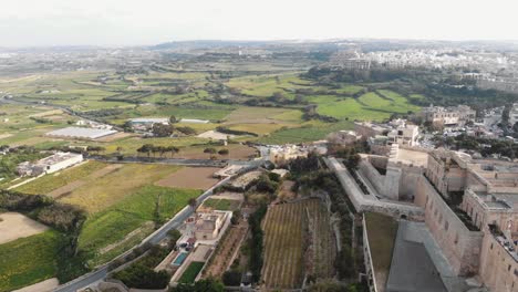 Mdina,-the-silent-city,-panoramic-view-outside-city-walls-overlooking-the-Maltese-landscape,-in-Malta---Aerial-fly-forward-shot